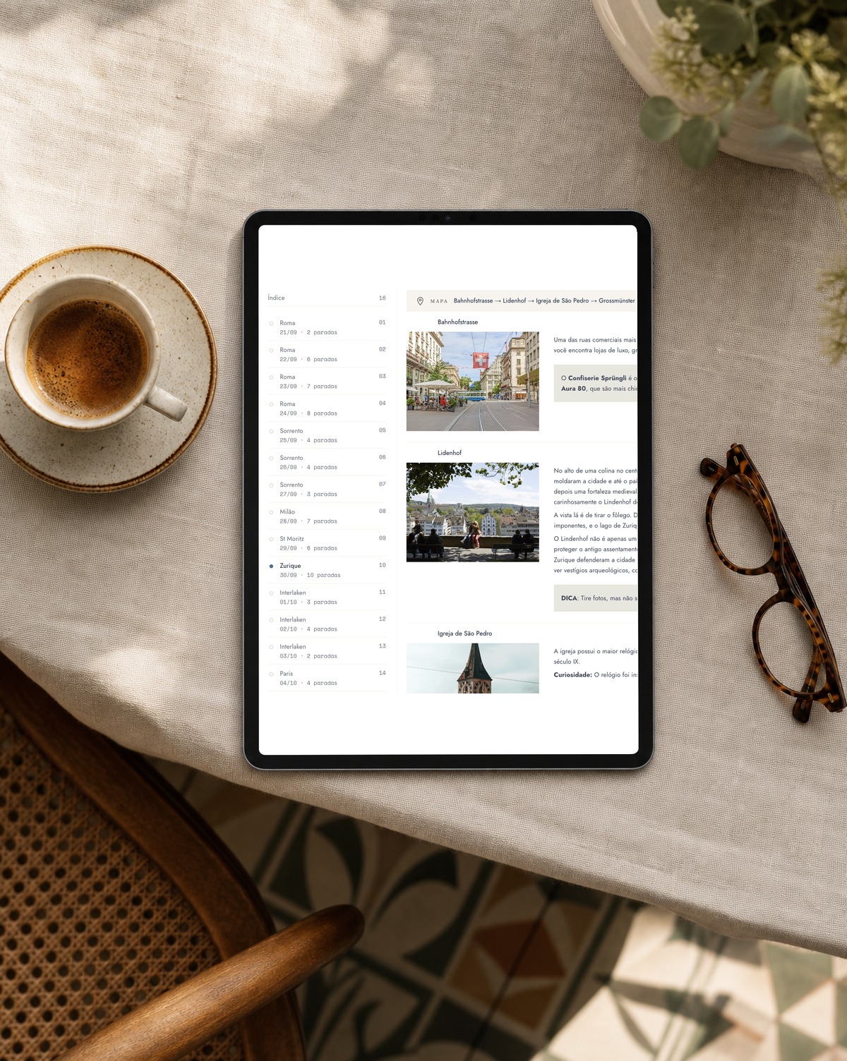 Tablette avec l'itinéraire de voyage posée sur une table, avec un café et des lunettes